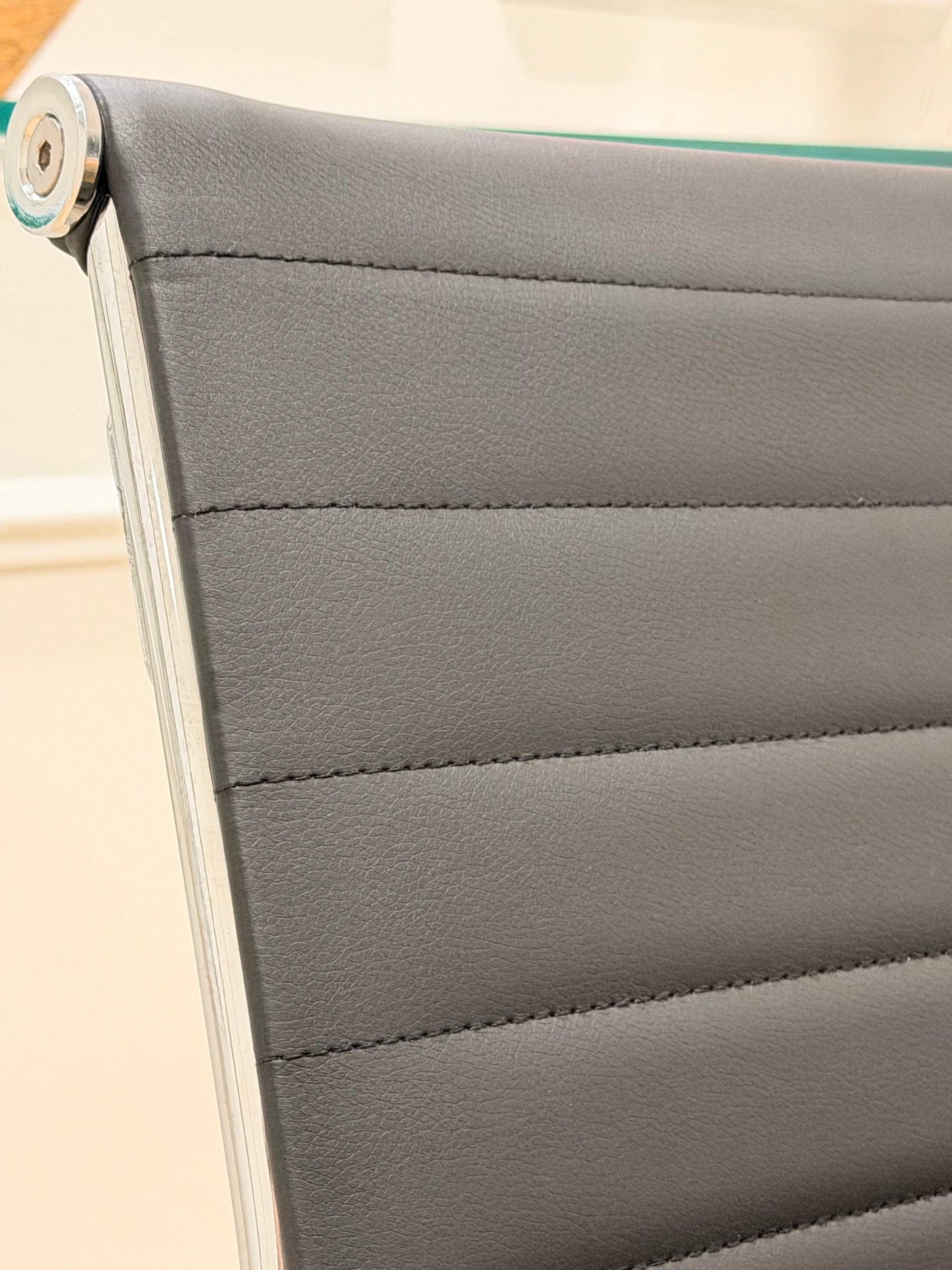 Close up detail of black ribbed leatherette backrest with durable metal chrome rim