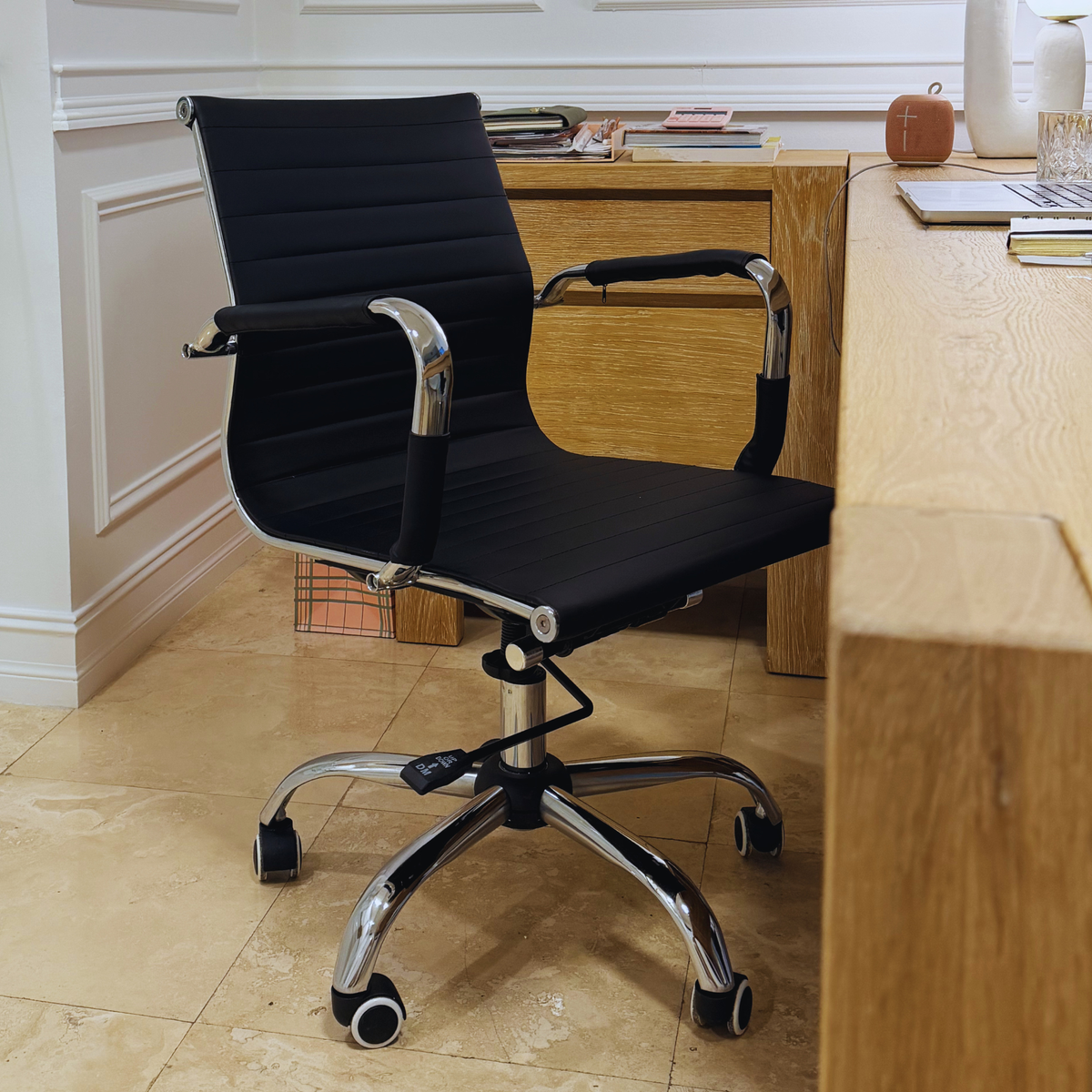 Black Mid-Century Modern desk chair placed at a natural wood study desk in a home office