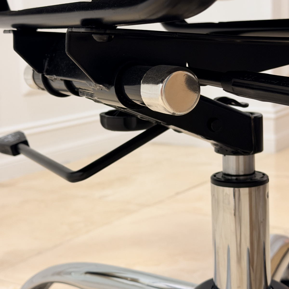 Detailed view of under-seat tilt tension control knob and height adjustment mechanism