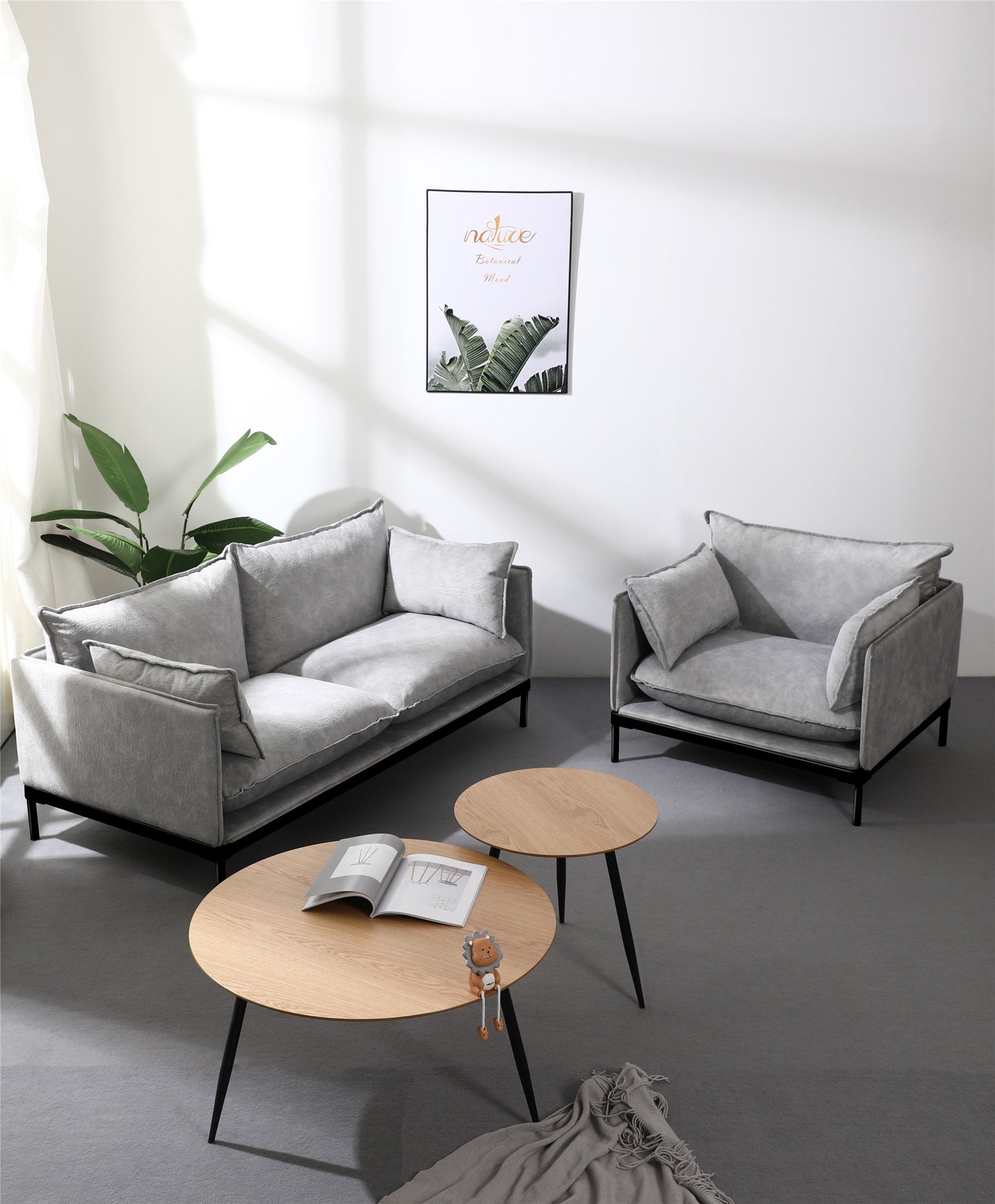 Modern reception room setup with upholstered grey sofa single armchair and round wooden coffee table