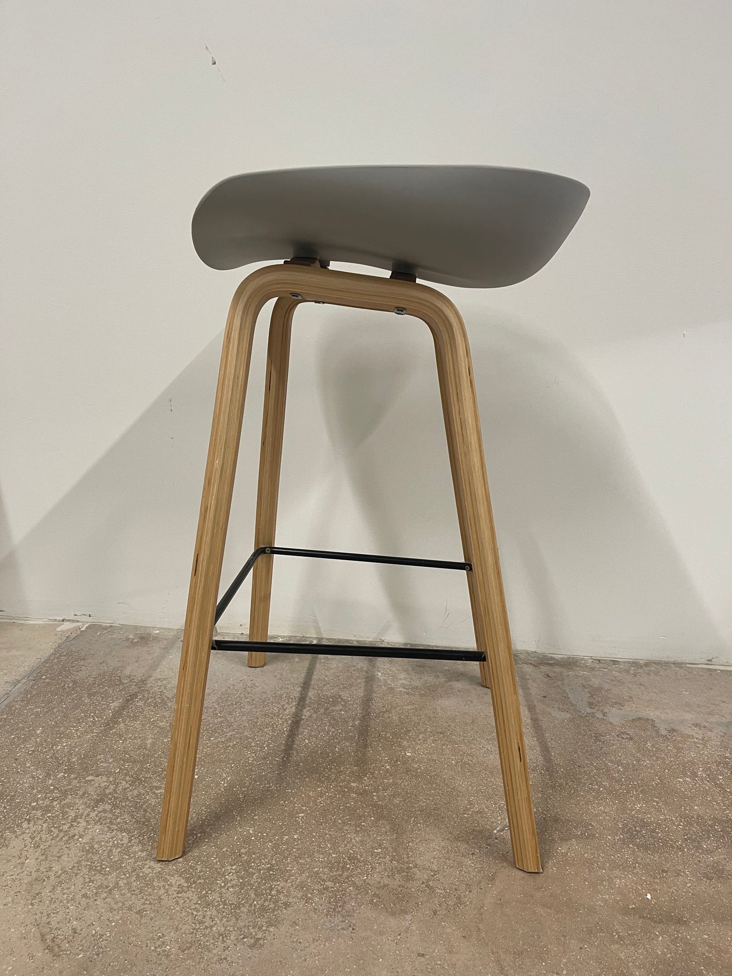 Front view of Scandinavian counter stool with wooden legs and black footrest